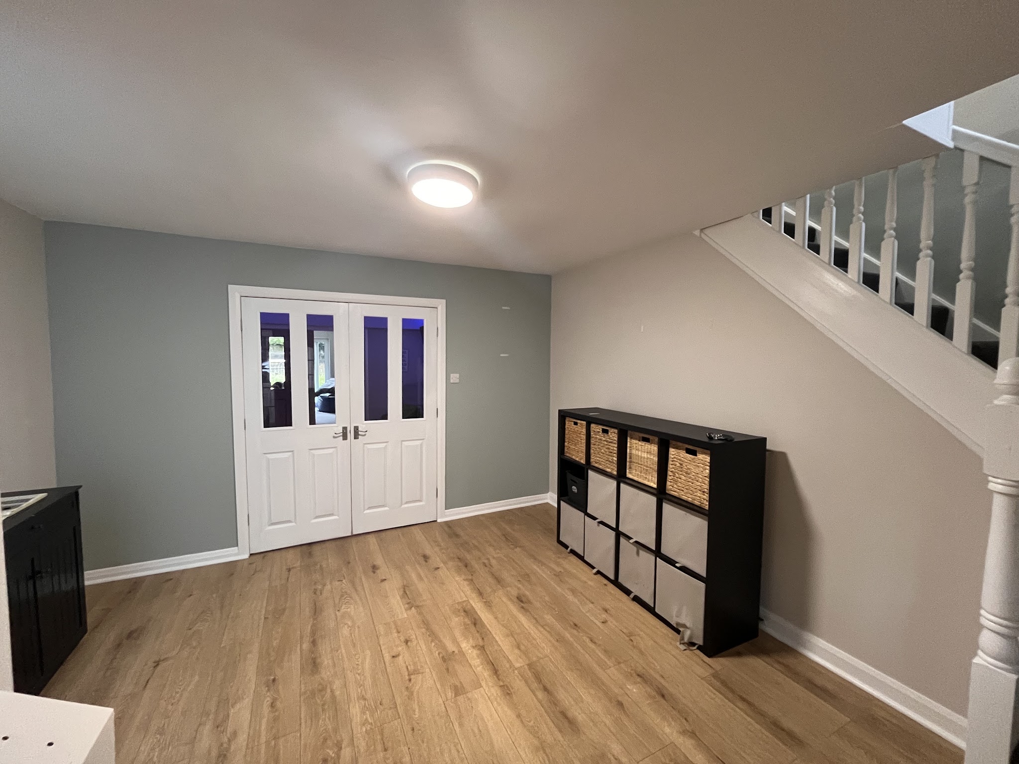 A freshly painted hallway with double doors, a staircase and a wood floor