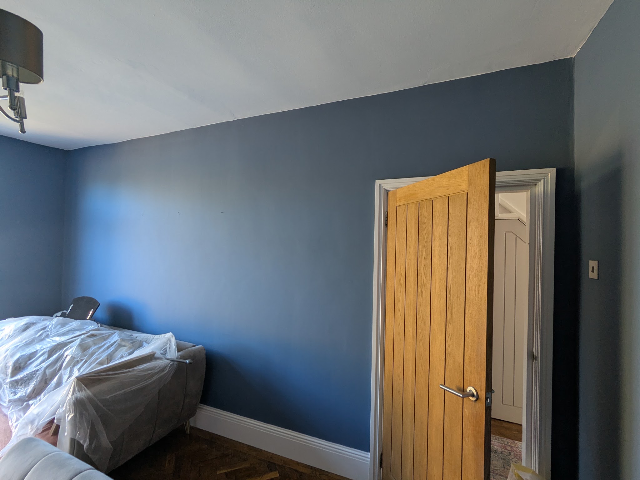A bedroom painted deep blue with an oak door