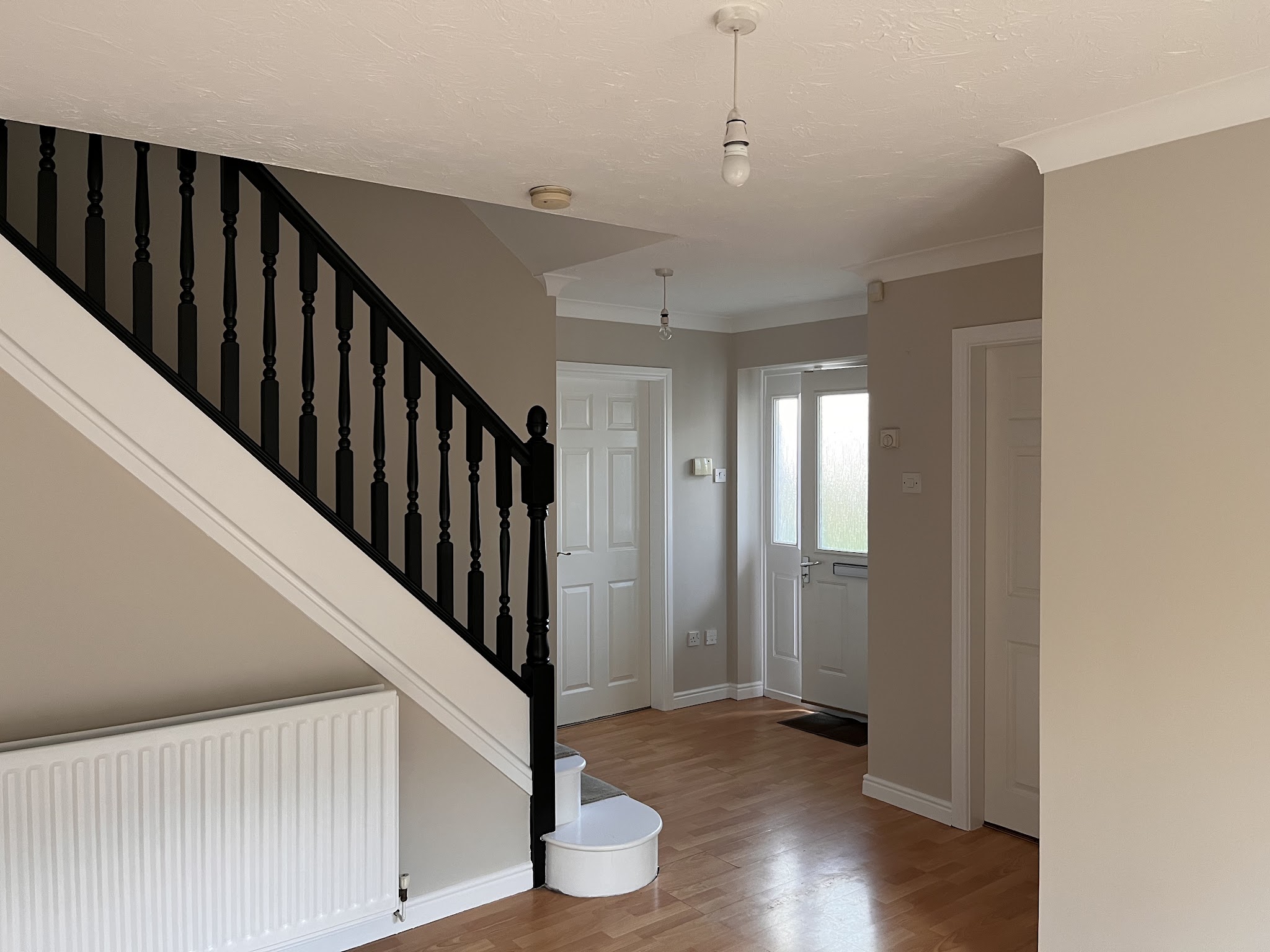 A hallway with a black painted banister and stairs